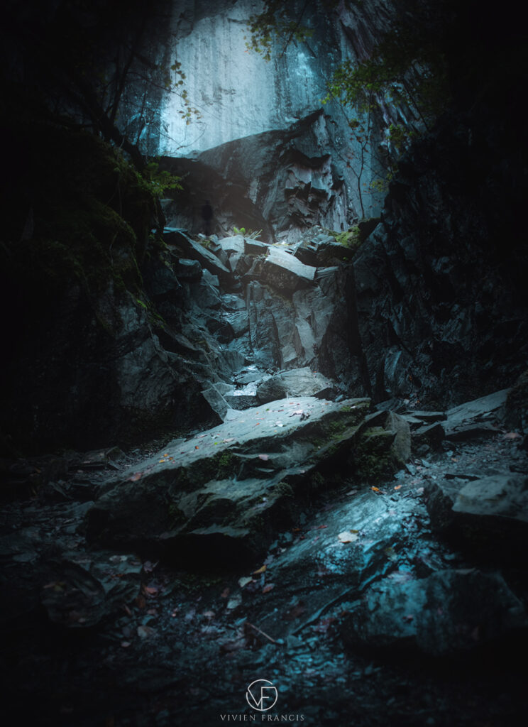Light cascading down into a cave filled with dark slate and gravel