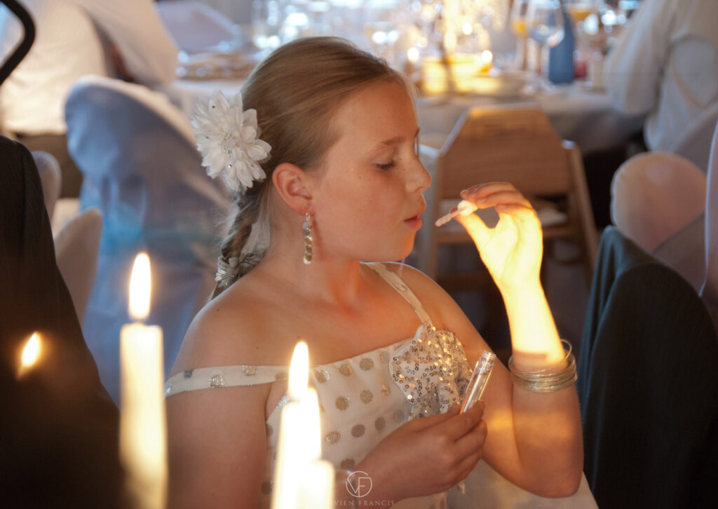 Little girl with flower in her hair and glitter dress blowing bubbles with candlelight