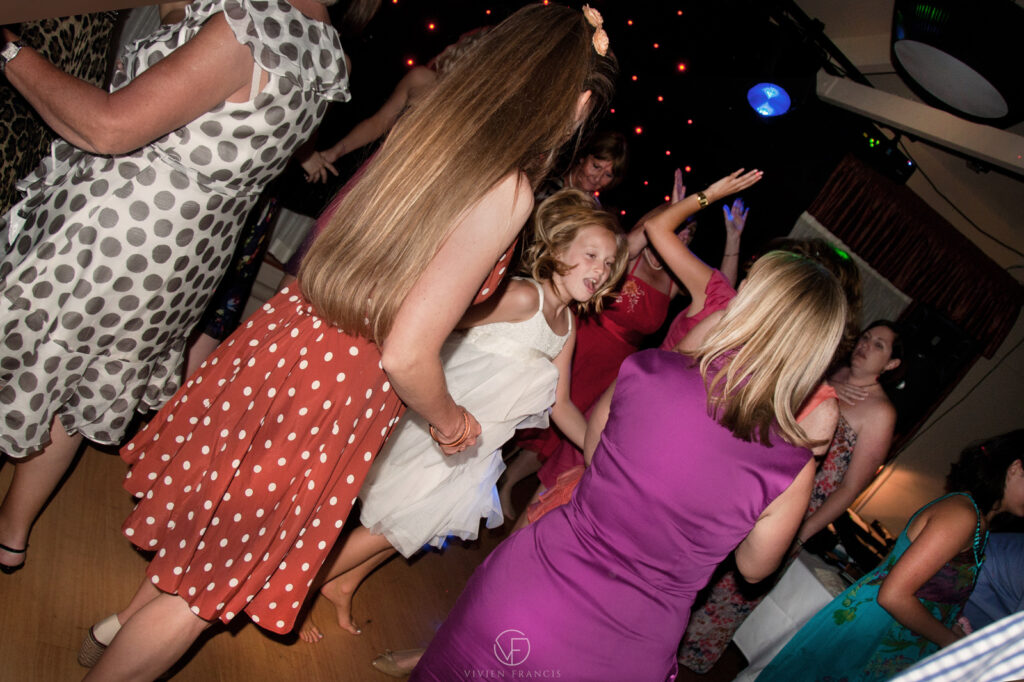 Little girl dancing with other women in pretty dresses and disco lights