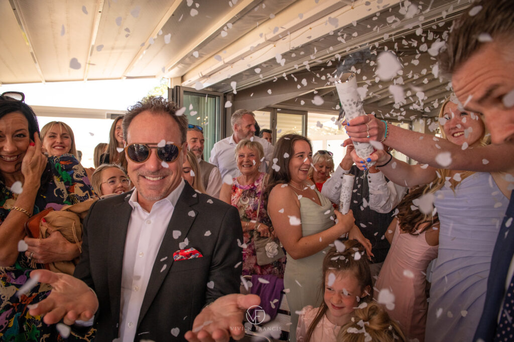 Guests smiling whilst white confetti is being shot inside the venue