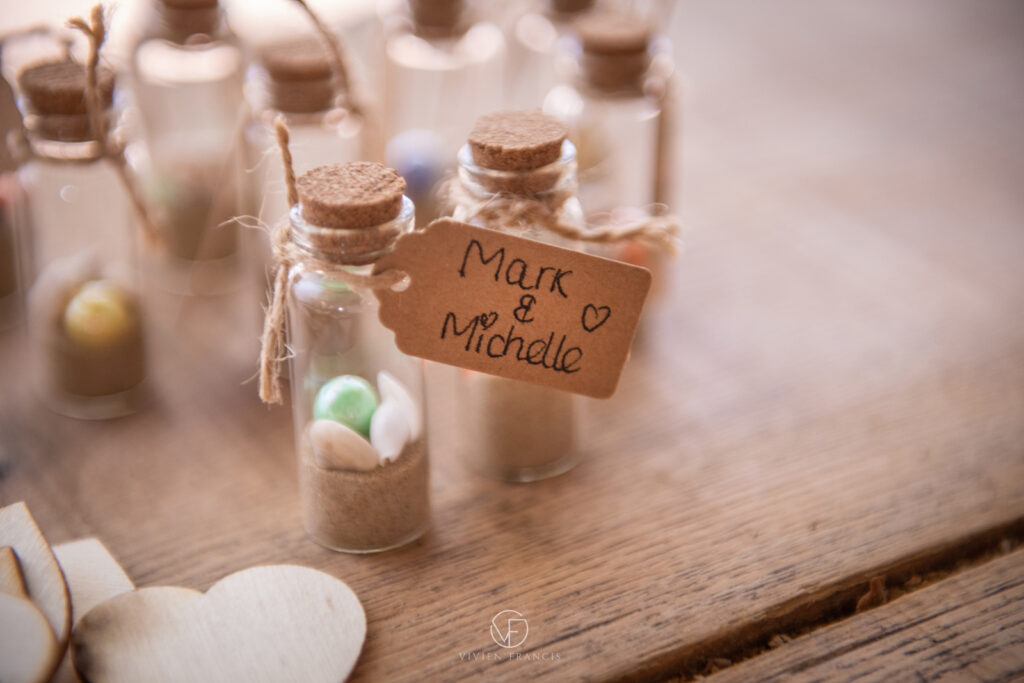 Tiny bottle with sand, a coloured pearl and tiny shells with a rope and tag with the wedding couple's name handwritten