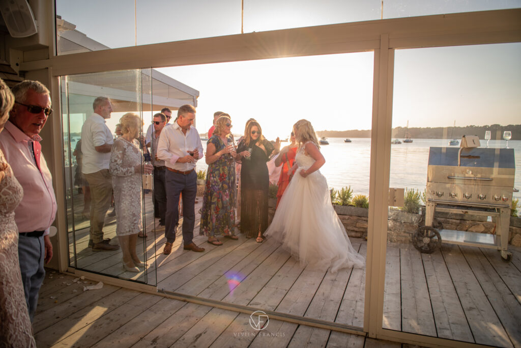 Sun star across a venue with bride holding her dress, with guests standing around her