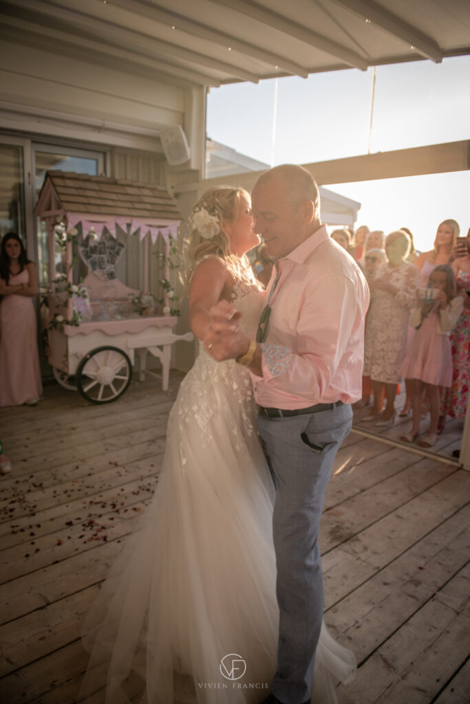 Bride and groom dancing in a beautiful sunset-lit room with rose petals on the floor
