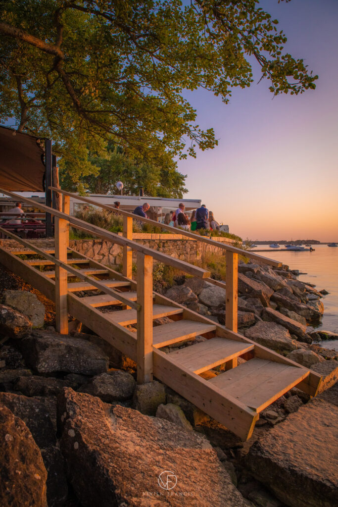Wooden stairs to restaurant with trees and rocks and the sea at golden hour