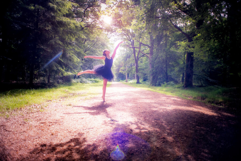 Lady with black ballet outfit posing with sunlight behind her and trees surrounding her